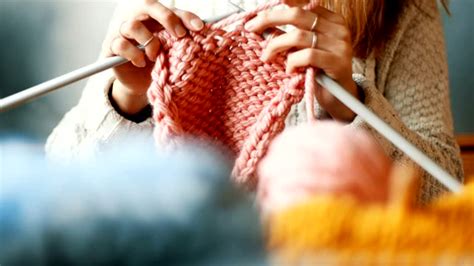 Gros plan sur une main tricotant un petit vêtement de poupée