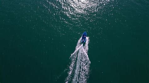 Vue aérienne d'un bateau naviguant sur une mer calme, avec un masque mystérieux flottant à proximité.