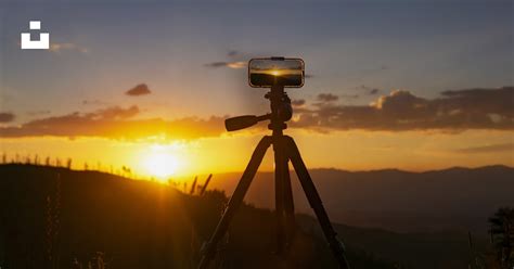 Un appareil photo sur un trépied face à un coucher de soleil.
